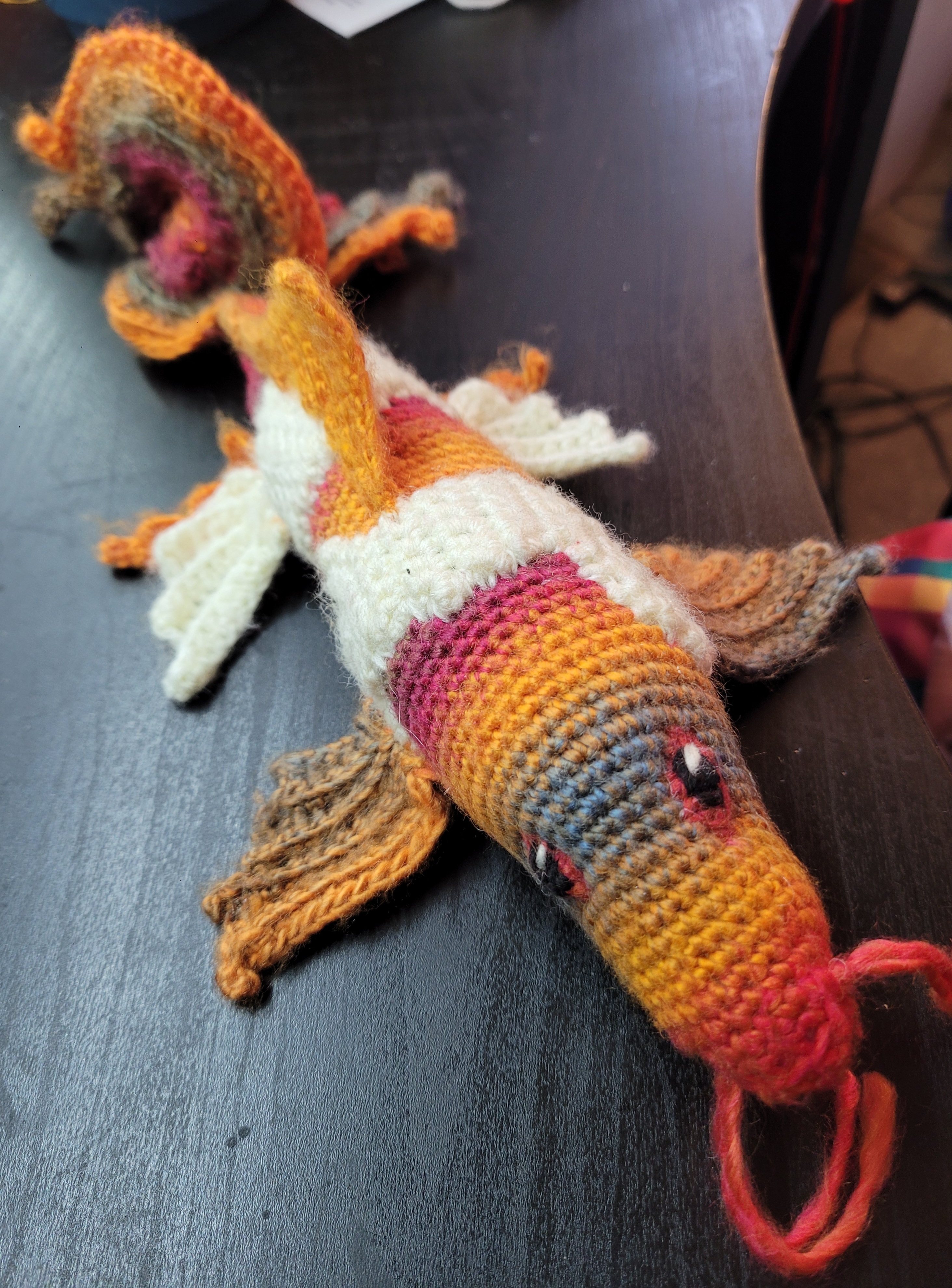 Crochet koi plush with an orange, pink, grey, and white body, flowing fins, and embroidered eyes.